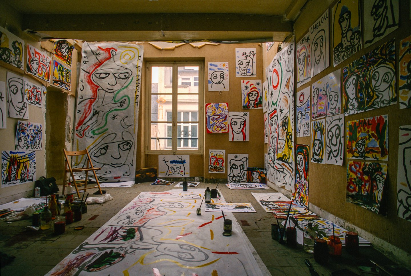 Studio d'artista pieno di dipinti astratti e materiale artistico.