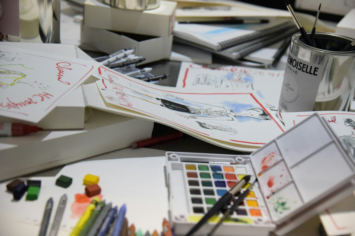 Schizzi di moda e materiale artistico sparsi su una scrivania da designer.